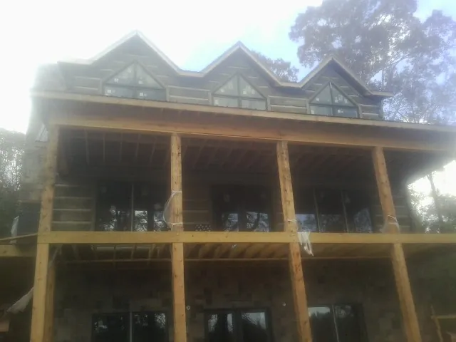 Dormers and porch framing on a large log home under construction — Roof Coating work by our crew in Huntington Mills