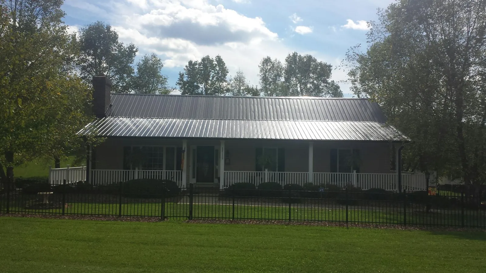 Gray metal roof on a brick ranch with a full width front porch — Gutter Guard Installation work by our crew in Huntington Mills