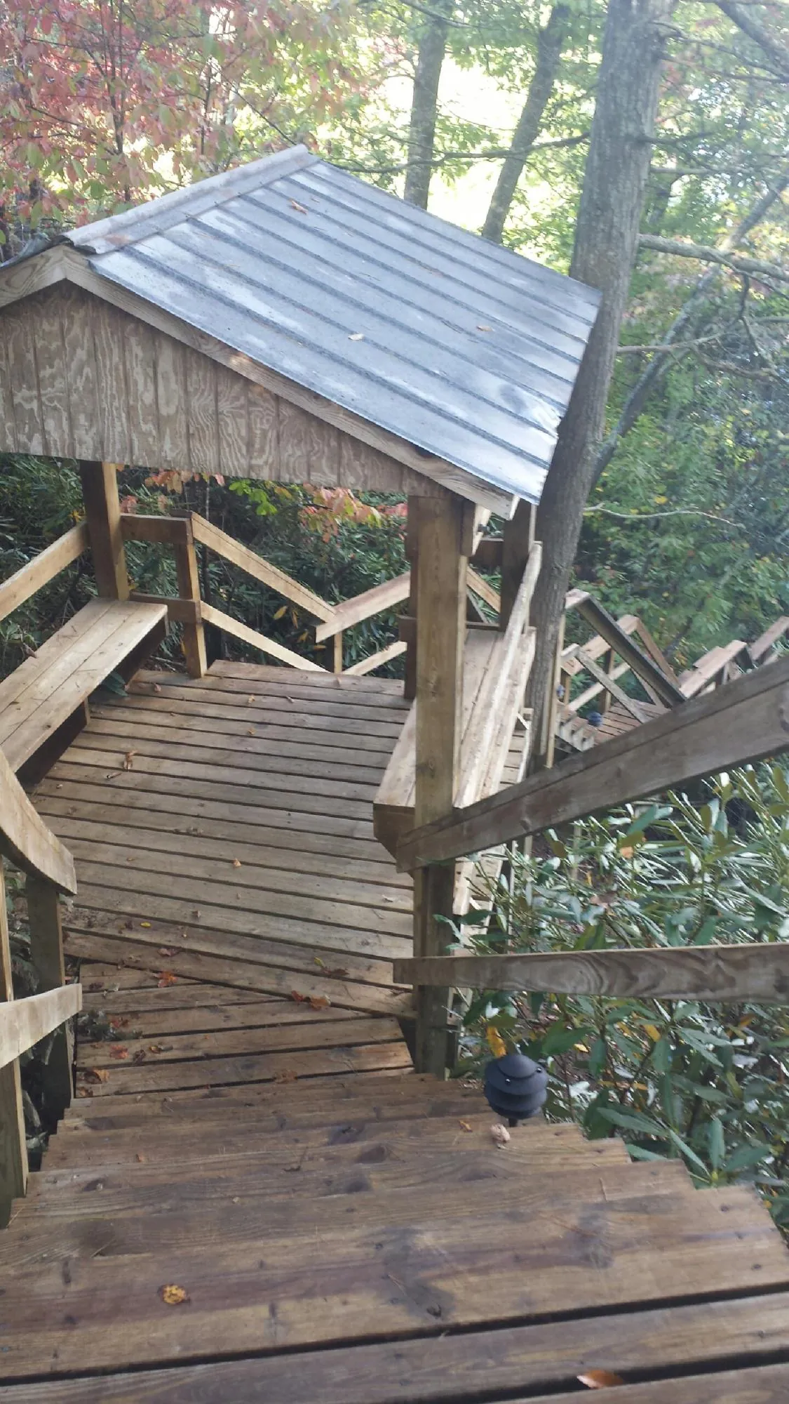 Metal roofed shelter over wooden steps on a wooded walkway — Skylight Repair & Installation work by our crew in Huntington Mills