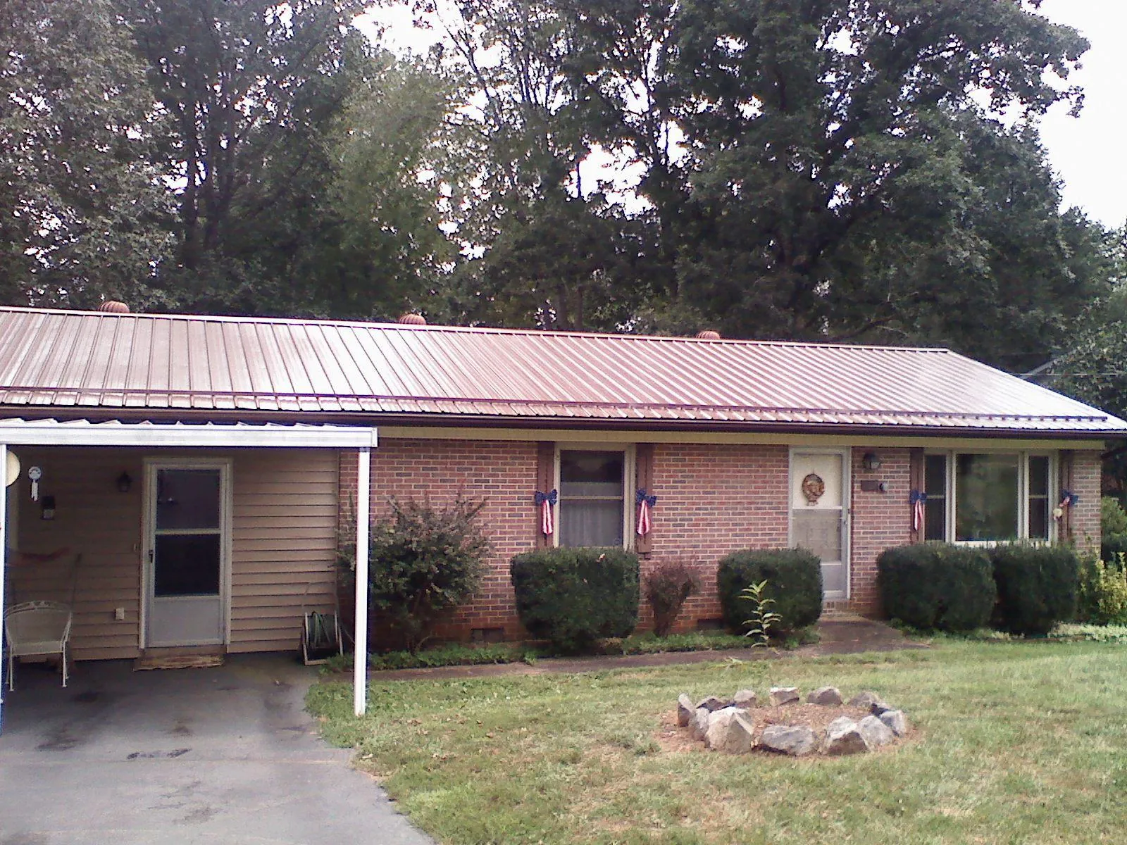 Bronze metal roof and carport on a brick ranch home — Roof Repair work by our crew in Huntington Mills